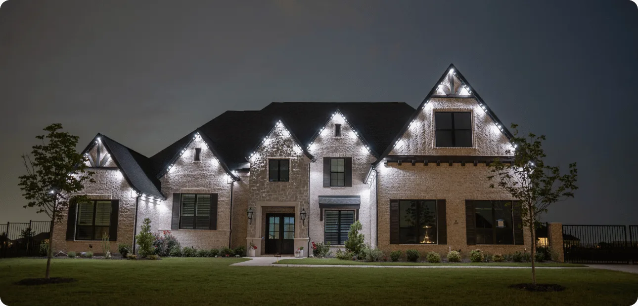 Home exterior with warm white permanent lighting along the roofline at dusk