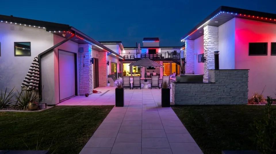 Close-up of warm white permanent lights tucked into the roofline of a stone home